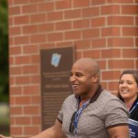 Guests holding his arms out, holding a football at the Jamie Hosford Football Center dedication.